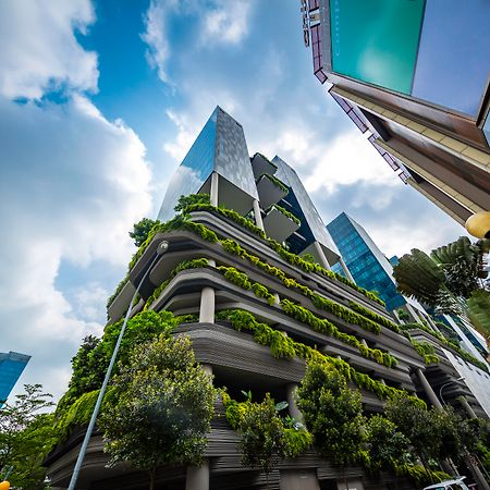Parkroyal Collection Pickering, Singapura Luaran gambar The photo shows a modern urban setting featuring contemporary buildings. In the foreground, there is a distinctive structure with a green façade, showcasing various plants and greenery integrated into the architecture. The design appears to emphasize