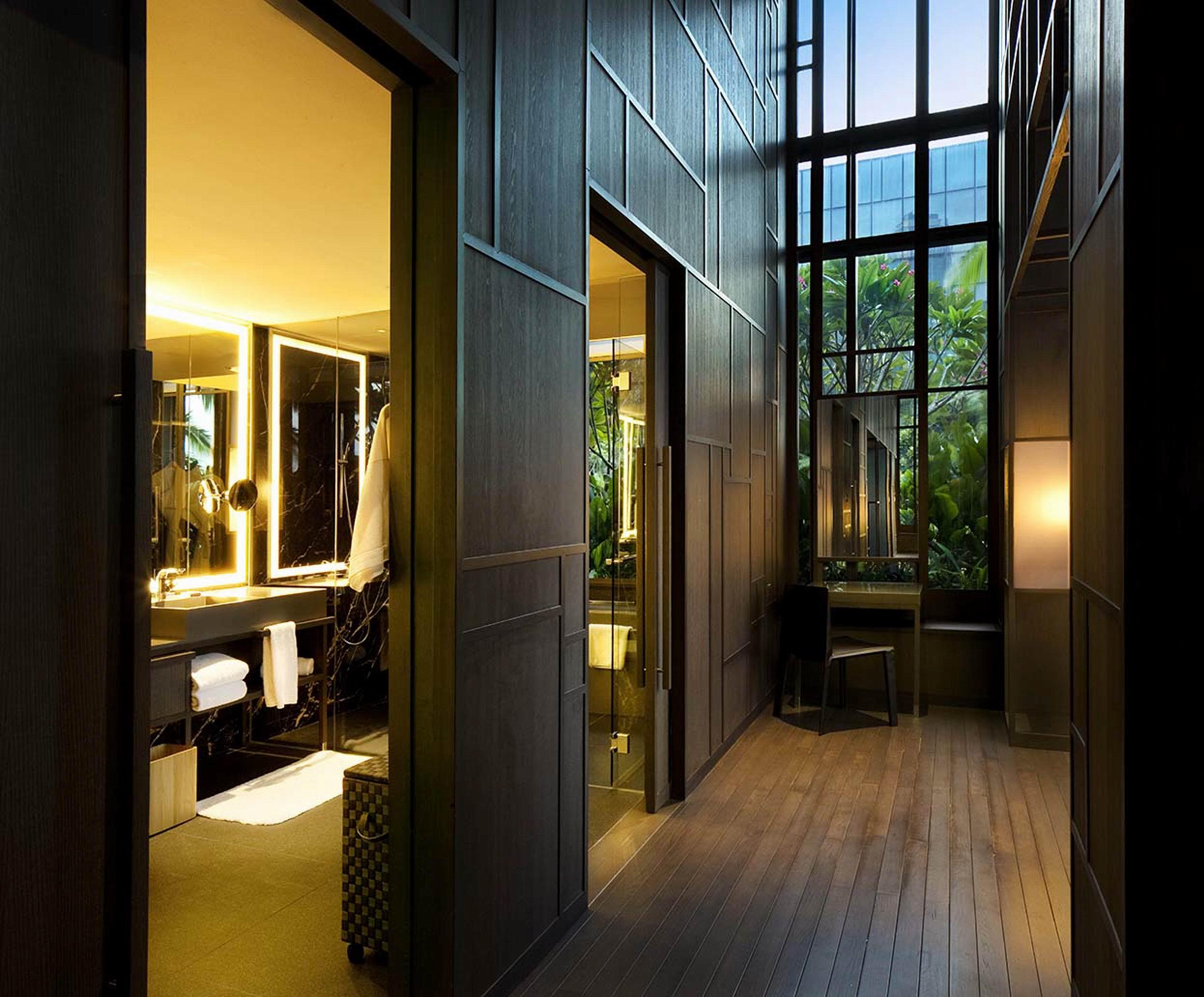 Parkroyal Collection Pickering, Singapura Luaran gambar The photo depicts a modern interior space, likely a hotel or luxury residence, featuring a hallway with large windows that allow natural light to enter. On one side of the hallway, there are partially open doors leading to rooms, possibly bathrooms o