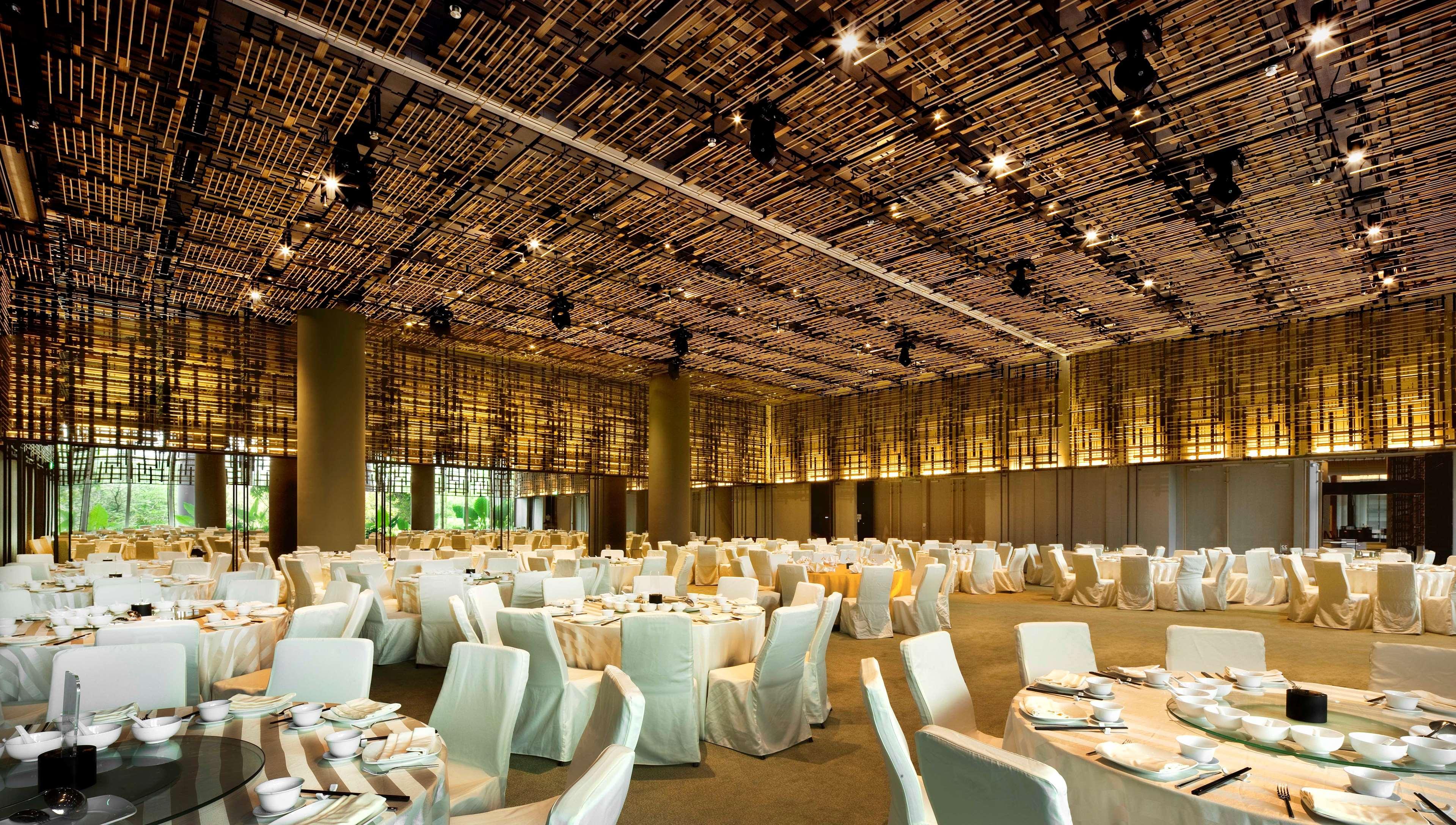 Parkroyal Collection Pickering, Singapura Luaran gambar The photo shows an elegantly designed banquet hall. The ceiling features a unique design made of woven materials, creating a warm ambiance. The room is filled with round tables covered in cream-colored tablecloths, and each table is set with plates a