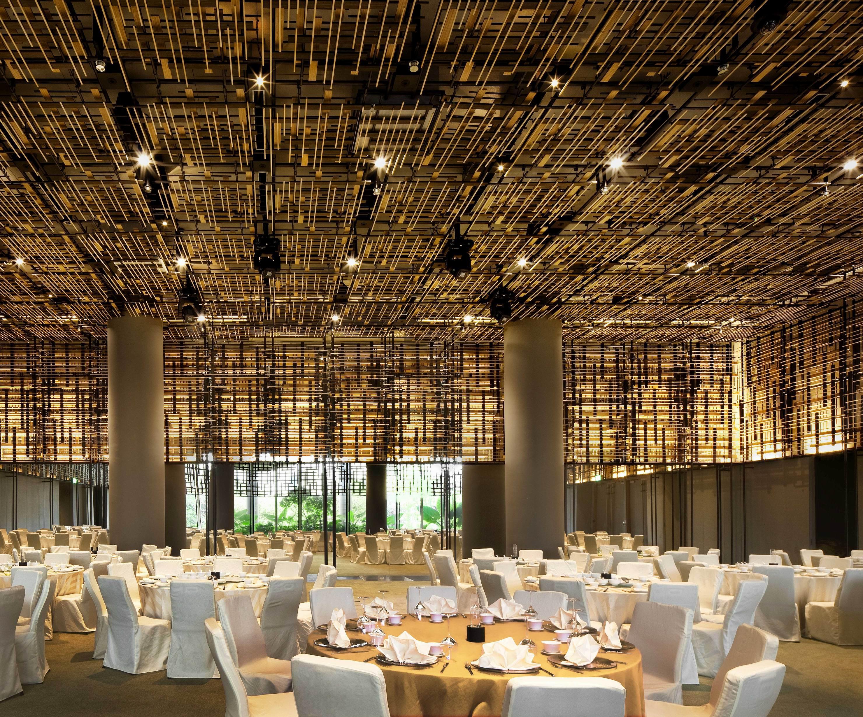 Parkroyal Collection Pickering, Singapura Luaran gambar The photo shows a spacious dining area with a modern and elegant design. The ceiling features a unique installation of bamboo or wooden elements that creates a textured appearance. The room is filled with round tables, each set with white tablecloths