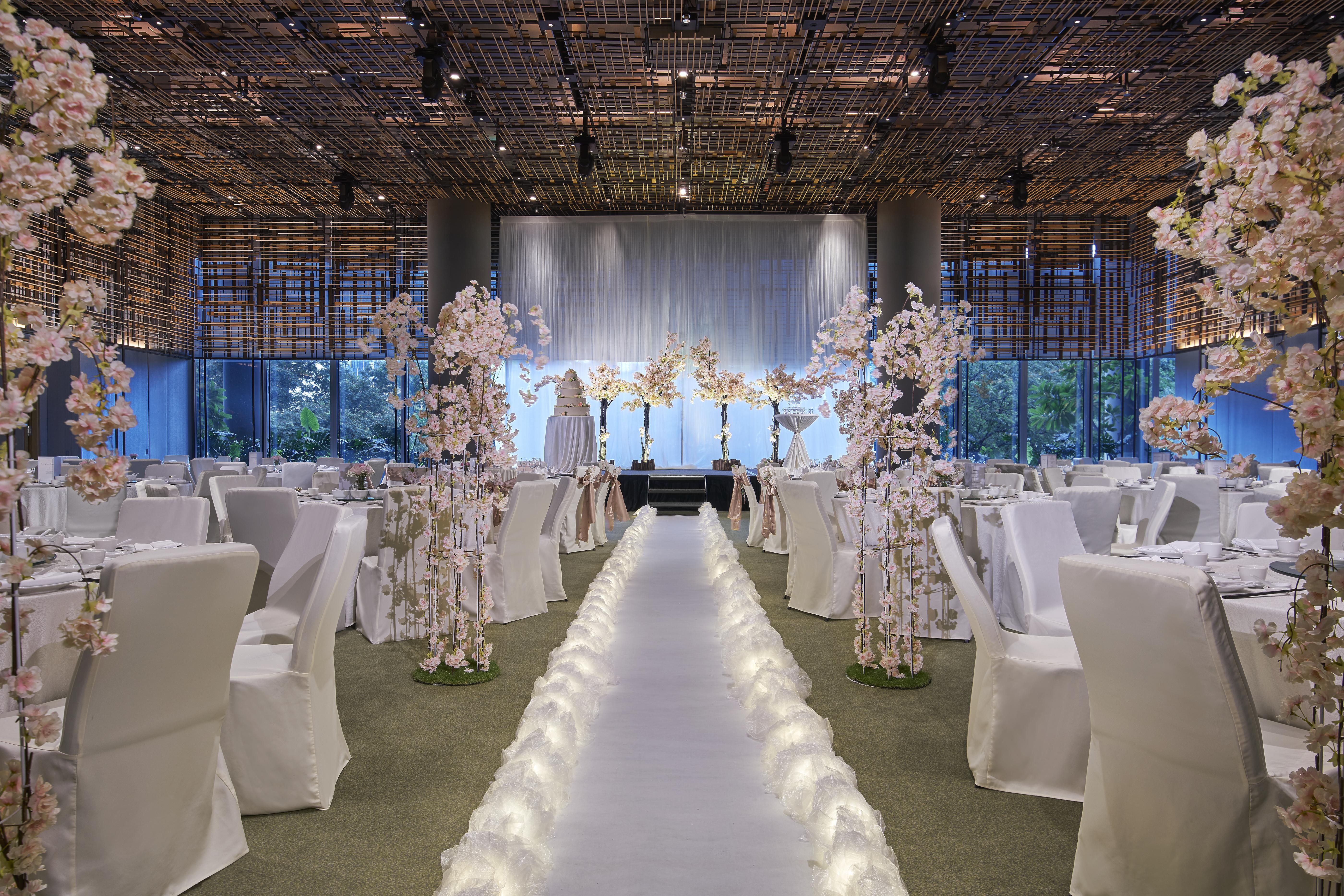 Parkroyal Collection Pickering, Singapura Luaran gambar The photo showcases an elegantly decorated indoor venue, likely set up for a wedding or formal event. The space features tables draped in white cloths, with surrounding chairs that match. 

A prominent aisle runs down the center, illuminated by soft 