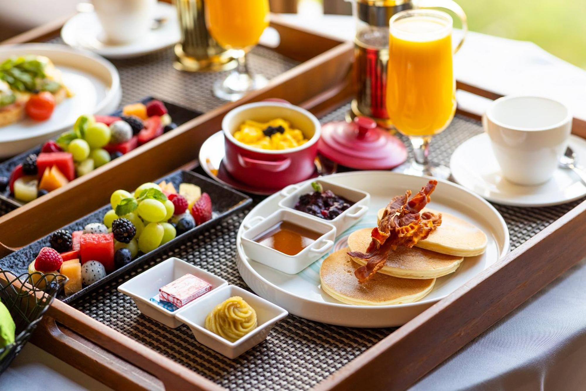 Parkroyal Collection Pickering, Singapura Luaran gambar The photo shows a beautifully arranged breakfast tray. It includes:

- A stack of pancakes served with crispy bacon.
- Small bowls of syrup and fruit preserves.
- Slices of fresh fruit, including a variety of berries and grapes.
- A small dish with w