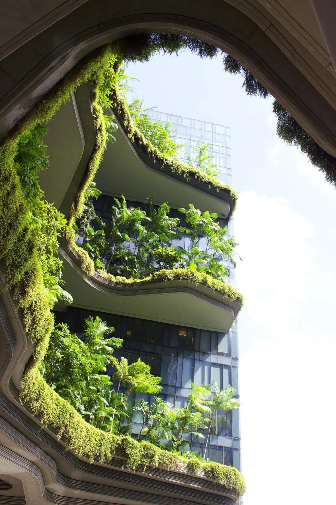 Parkroyal Collection Pickering, Singapura Luaran gambar The photo shows a modern building featuring several balconies adorned with lush greenery. The balconies have a wavy design, giving them an organic appearance. Various plants, including tropical foliage, are prominently displayed, creating a striking 