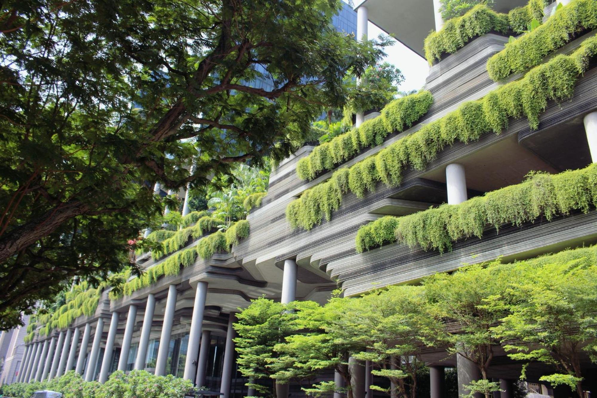 Parkroyal Collection Pickering, Singapura Luaran gambar The photo shows a modern building with a unique architectural design. The structure features multiple levels supported by several columns, and it is adorned with abundant greenery. Plants are cascading down from the balconies or ledges, giving the bu